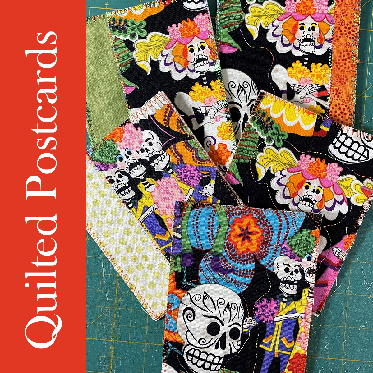 several quilted postcards featuring Dia de los Muertos fabric arranged on a green cutting mat