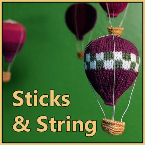 Four knitted hot air balloons against a green background, with the caption "Sticks & String"